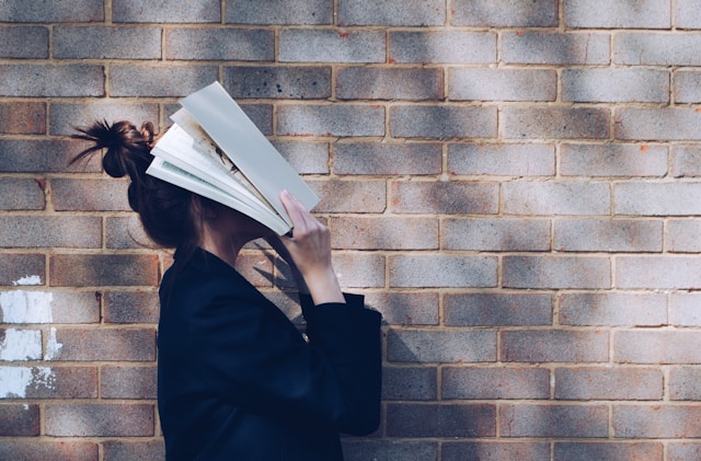 Tired woman putting papers and rulebooks over her face.